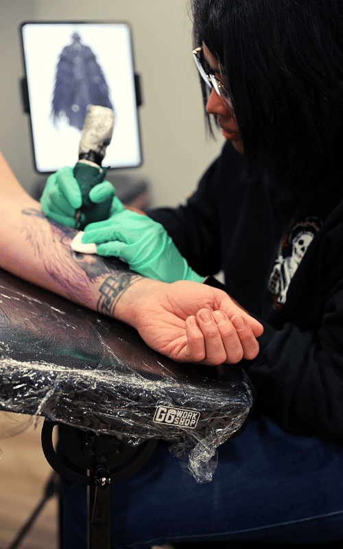 Bianca tattooing a client
